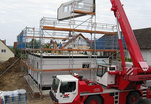 Kran hebt Fertigteil auf einen Rohbau