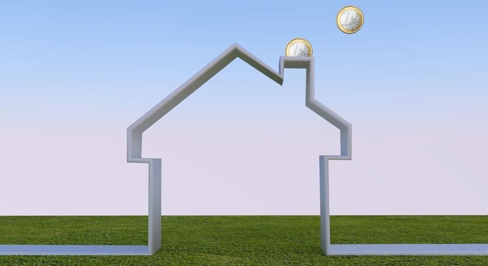 Hausumriss mit 2-Euro-Münzen im Schornstein – Bauzinsen 2026